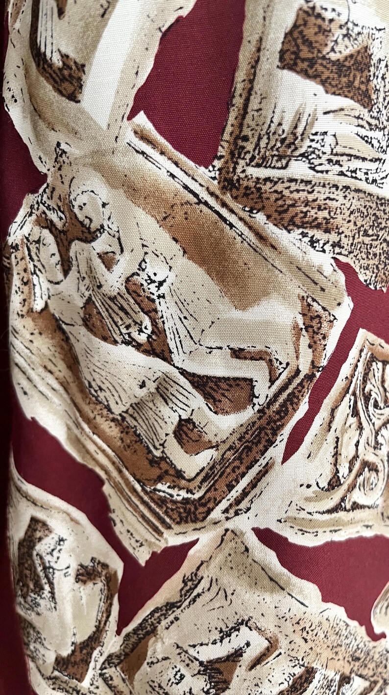 以下が含まれることがあります： 茶色と白のスタイリッシュな人物が描かれた赤い布。人物は抽象的で、人や動物のように見える。