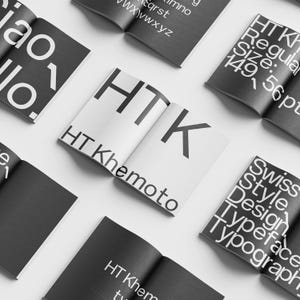 Può includere: Primo piano di un opuscolo in bianco e nero con il testo "HT Khemoto" e "HTK" in grassetto, carattere grande. L'opuscolo è piegato a metà e il testo è visibile su entrambi i lati.