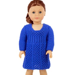 May include: A blue knitted dress with a textured pattern. The dress has long sleeves and a scoop neckline.