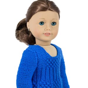 May include: A blue knitted sweater with a textured design. The sweater has a scoop neck and long sleeves.