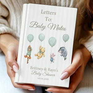 Könnte beinhalten: Ein personalisiertes Babyparty-Gästebuch mit hellgrün-weiß gestreiftem Einband. Das Buch zeigt den Text "Letters To: Baby Mateo" und Illustrationen von Winnie-the-Pooh-Figuren, die Ballons halten. Das Buch enthält auch den Text "Brittney & Rayn's Baby Shower" und das Datum.