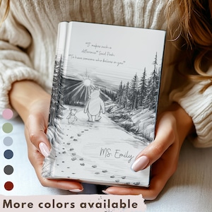 May include: A white journal with a pencil sketch of Winnie the Pooh and Piglet walking on a path. The journal has the quote, "It makes such a difference" and "To have someone who believes in you." The name "MS. Emily" is written on the journal.