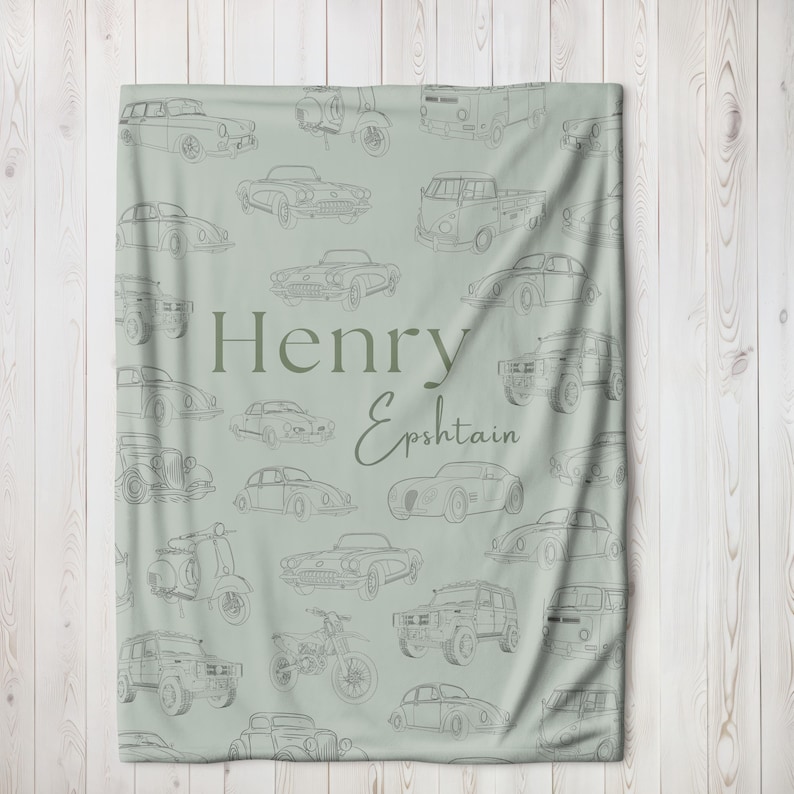May include: A light green blanket featuring a pattern of vintage car illustrations in gray. The blanket has the name "Henry Epshtain" printed in a darker green font. The design includes various car models, motorcycles, and scooters.