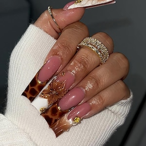 Uñas postizas de lujo con efecto mármol marrón, elegantes uñas postizas para otoño, uñas otoñales con detalles en blanco y flores 3D doradas, uñas marrones.