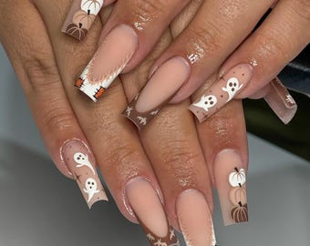 May include: Long square-shaped artificial nails featuring a nude base with various designs including white and brown stacked pumpkins, white ghosts, small brown bats, and orange and white checkered patches on a white background with brown tips.