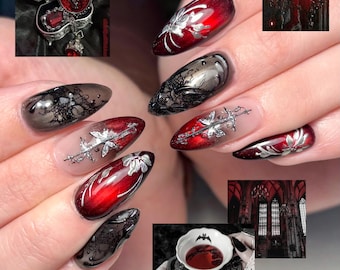 May include: Almond-shaped nails featuring a mix of deep red and black polish with intricate silver metallic floral and filigree accents. The design includes translucent sections, dark lace-like patterns, and glossy finishes, creating a layered look.
