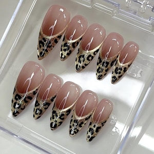 Puede incluir: Un juego de diez u&ntilde;as postizas en forma de almendra con una base de color nude y un dise&ntilde;o de punta francesa. Las puntas est&aacute;n decoradas con un fondo de purpurina dorada y un estampado de leopardo negro. Las u&ntilde;as est&aacute;n dentro de una caja transparente.