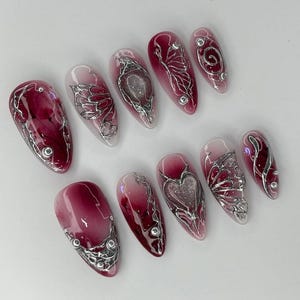 Uñas postizas 3D en cromo rojo, diseño de corazón metálico color vino, uñas con alambre plateado Y2K, uñas postizas en color vino tinto para ocasiones especiales, uñas cromadas imagen 3