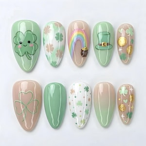 May include: A set of ten artificial nails with St. Patrick's Day designs. The nails feature shamrocks, rainbows, leprechaun hats, and gold coins in shades of green, white, and gold. Some nails have a light pink or nude base.