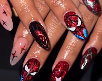 May include: Almond-shaped nails featuring a variety of designs including red glitter Spider-Man masks with white eyes, metallic silver and red polka dots, a solid red glitter nail with a white star, and a nude base with small red star accents.