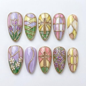 May include: Ten oval nail art designs with a stained-glass effect. Each nail has gold outlines and features designs such as flowers, crosses, and geometric patterns. The colour scheme includes pastels like pink, purple, yellow, and green.