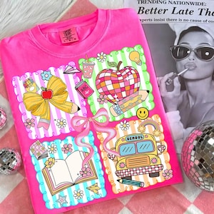 May include: A bright pink Comfort Colors sweatshirt featuring four colorful school-themed designs. The designs include an apple, a school bus, a book, and a bow, all with floral and striped accents. The shirt has the Comfort Colors label.