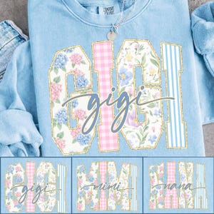 May include: Light blue sweatshirt with the word "GIGI" in large, floral-patterned letters outlined in gold. The word "gigi" is written in cursive below. Additional designs with "MIMI" and "NANA" are shown below.