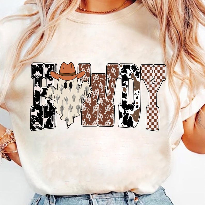 K&ouml;nnte beinhalten: Cremefarbenes T-Shirt mit dem Wort "Howdy" in einem Western-Design. Die Buchstaben sind mit Mustern wie Kuhdruck, Kakteen und einem Schachbrettmuster gef&uuml;llt. Ein Geist mit Cowboyhut befindet sich in der Mitte.