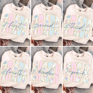 May include: Cream-coloured sweatshirts with the words "First Grade", "Second Grade", "Third Grade", "Fourth Grade", "Kinder", and "Pre-K" in a floral and striped design. The sweatshirts are displayed on a denim background.
