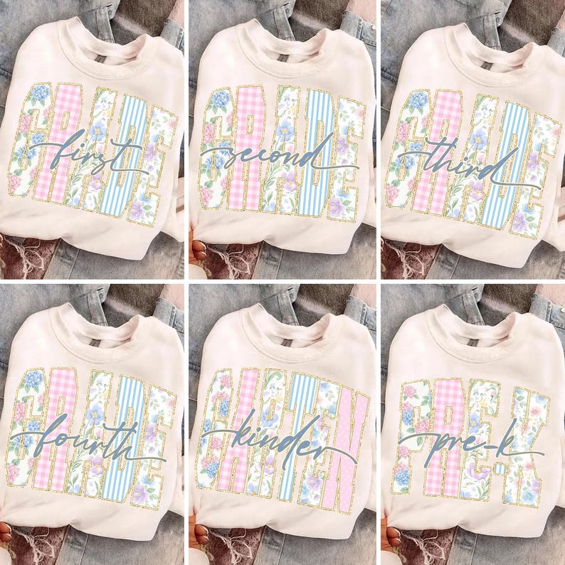 May include: Cream-coloured sweatshirts with the words "First Grade", "Second Grade", "Third Grade", "Fourth Grade", "Kinder", and "Pre-K" in a floral and striped design. The sweatshirts are displayed on a denim background.