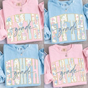 May include: Four crewneck sweatshirts in light pink and light blue, each featuring a large block-letter graphic filled with floral and striped patterns. The text reads Sixth, Fifth, Eighth, or Seventh grade in a cursive script overlay.