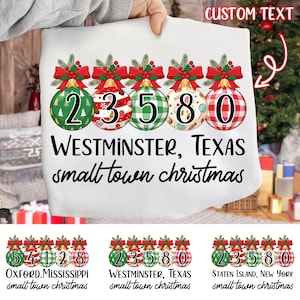 Może przedstawiać: Biała torba na zakupy o tematyce świątecznej z pięcioma ozdobami z numerami 2, 3, 5, 8 i 0. Każda ozdoba ma inny wzór i jest ozdobiona czerwoną kokardą i zielenią. Pod ozdobami znajduje się napis "WESTMINSTER, TEXAS small town christmas".