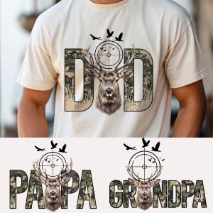 May include: Cream-colored t-shirt featuring the word "DAD" in a camouflage pattern, with a deer head inside the letter "D". Above the deer is a target with birds flying around it. Below are the words "PAPA" and "GRANDPA" with similar designs.