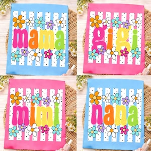 May include: Four rectangular fabric items featuring vertical white stripes with black dots. Each item displays colorful flowers and the words mama, gigi, mimi, or nana in large, rounded, multi-colored lettering across the center.