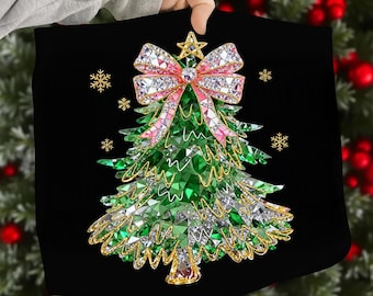 May include: Black square pillow featuring a Christmas tree design. The tree is made of green and silver crystals, with a pink and crystal bow at the top. Gold snowflakes and a star accent the design. The pillow is held by a person.