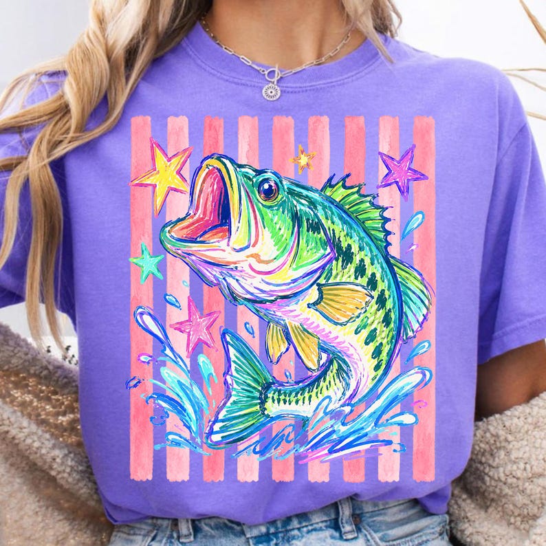 Op de afbeelding: Paarse t-shirt met een kleurrijke afbeelding van een springende vis, waterspetters en sterren. Het ontwerp bevat roze verticale strepen. Een casual, comfortabel t-shirt.