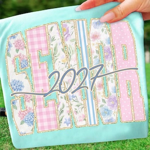 May include: A light blue t-shirt with the word "SENIOR" in a collegiate font, with the year "2027" in the center. The letters are filled with floral, gingham, and polka dot patterns, outlined in gold.