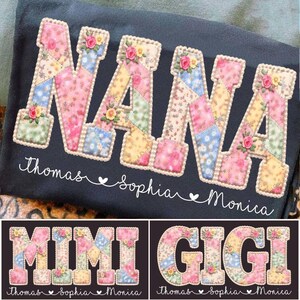 May include: A dark grey fabric item with the word "NANA" in large, colourful patchwork letters, each decorated with small floral accents. Below, the names "Thomas", "Sophia", and "Monica" are written in cursive.