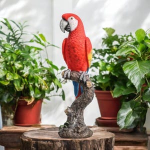 Puede incluir: Un loro guacamayo rojo y amarillo posado en una rama de árbol marrón. El loro es una estatua realista y es una gran adición a cualquier jardín o decoración del hogar.