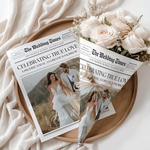 Op de afbeelding: Een trouw-krant met de kop "CELEBRATING TRUE LOVE" en de tekst "A PROMISE TODAY, A FOREVER TOMORROW". De krant bevat een foto van een stel en wordt vergezeld door een boeket witte rozen. De krant ligt op een houten dienblad.