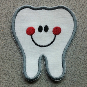 May include: Embroidered patch of a smiling tooth. The white tooth has a grey border, two red cheek circles, two black eyes, and a black curved smile. Ideal for dental-themed projects.