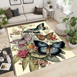 May include: A cream-colored rug with a floral design featuring butterflies in shades of blue, purple, orange, and black. The butterflies are surrounded by green leaves and pink flowers.
