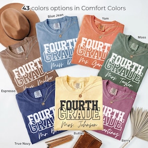 May include: Seven Comfort Colors t-shirts in various colors including espresso, blue jean, yam, moss, true navy, butter, and berry. Each shirt features the text FOURTH GRADE and a teacher's name in white or black ink, with a brown hat and pencils.
