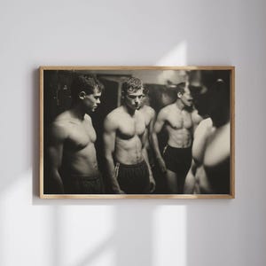 Könnte beinhalten: Schwarz-Weiß-Druck mit Rahmen, der eine Gruppe von Männern ohne Hemd in einem Umkleideraum zeigt. Die Männer tragen dunkle Shorts, was auf ein Sportteam hindeutet. Das Bild hat eine Vintage-Ästhetik in Sepia.