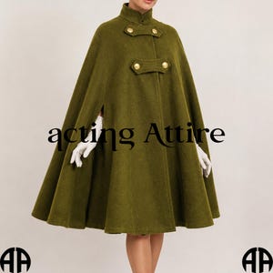 May include: Olive green cape with a high collar and gold-colored buttons. The cape has a flared silhouette and side slits for the arms. The text "acting Attire" is printed on the front.