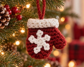 May include: A small, crocheted Christmas ornament shaped like a mitten. The mitten is deep red with a white cuff and a white snowflake applique on the front. It features a red yarn loop at the top for hanging on a tree branch.