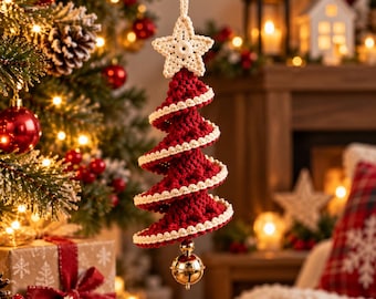 May include: A hanging Christmas tree ornament made of dark red crocheted yarn with cream-colored trim on the edges. The ornament features a crocheted star at the top and a small, shiny gold-colored metal bell hanging from the bottom point.