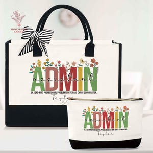 May include: A white tote bag and matching cosmetic bag with black accents. The bags feature the text "ADMIN ASSISTANT" in colorful letters with floral accents. The tote has black handles and a striped bow. The cosmetic bag has a black base.