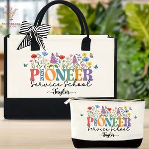 May include: A canvas tote bag and matching cosmetic bag set. The bags are white with black trim and handles. They feature a colorful floral design and the text "Pioneer Service School 2026 Taylor". The tote bag has a black and white striped bow.