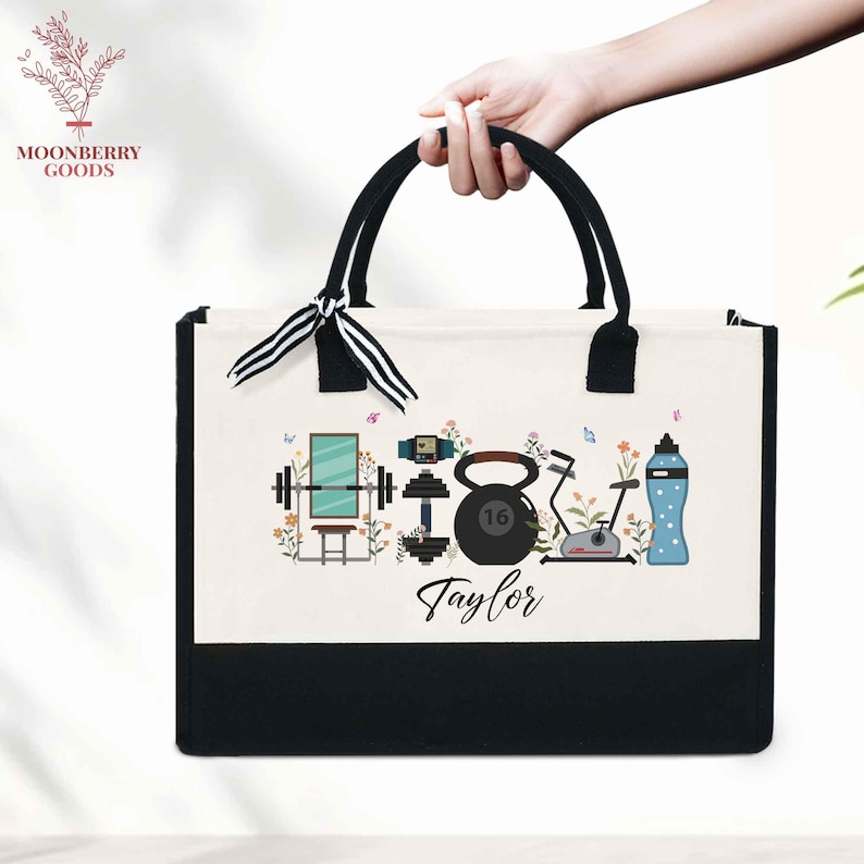May include: A canvas tote bag with black handles and a black bottom. The bag features a fitness-themed design with a barbell, kettlebell, exercise bike, and water bottle. The name "Taylor" is printed below the design.