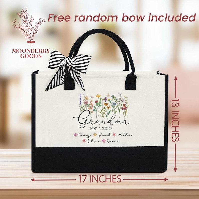 May include: White canvas tote bag with black handles and a black bottom. The bag has a floral design with the text "Grandma Est. 2025" and the names "Daisy, Jacob, Arthur, Olivia, Diana". The bag is 17 inches wide and 13 inches tall.