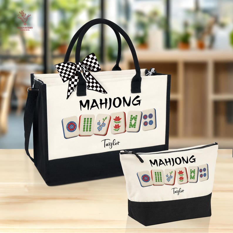May include: A white and black Mahjong tote bag and matching cosmetic bag. The bags feature the word "MAHJONG" and Mahjong tiles. A black and white checkered bow adorns the tote bag. The name "Taylor" is printed below the tiles.