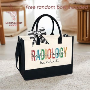 May include: A white canvas tote bag with black trim and handles. The bag has a colorful graphic that says "RADIOLOGY TECHNOLOGIST" with the name "Rachel" underneath. A black and white striped bow is attached to the handle.