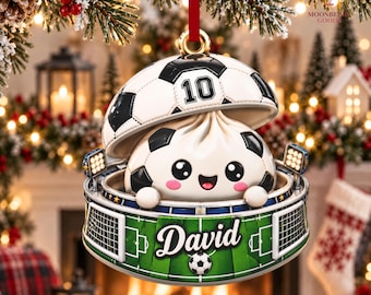 May include: A hanging ornament featuring a cartoon dumpling character inside a football stadium base with the name David printed on the green pitch. The top of the ornament is a football with the number 10, suspended by a red ribbon.