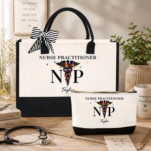 May include: A canvas tote bag and matching cosmetic bag, both featuring the text "NURSE PRACTITIONER" and a floral caduceus design. The tote has black handles and trim, and a striped bow. The cosmetic bag has a black base.