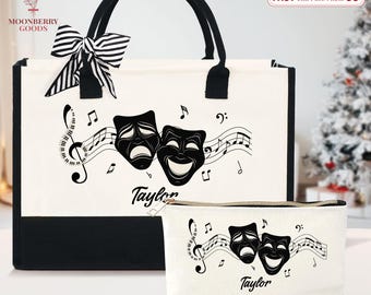 May include: A white tote bag and matching cosmetic bag with black accents. Both bags feature a musical note design with comedy and tragedy masks and the name "Taylor". The tote bag has a black and white striped bow.