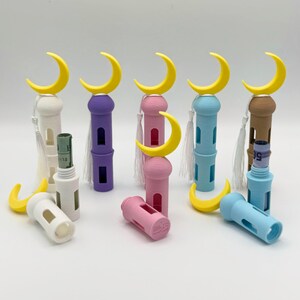 May include: Set of six colorful decorative containers shaped like minarets with crescent moon tops. Each container has a small opening and a tassel. The containers are in white, purple, pink, blue, and brown.