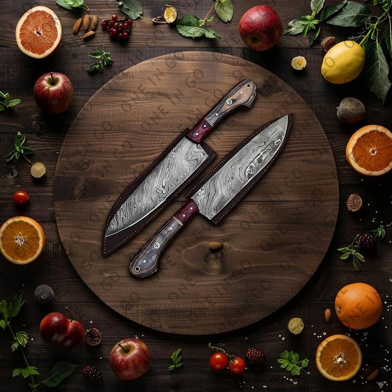 May include: Two kitchen knives with wooden handles and patterned blades are displayed on a wooden cutting board surrounded by fruit and greenery.