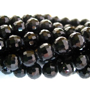May include: A strand of black faceted glass beads. The beads are round and have a shiny finish.