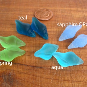 May include: Assortment of six glass sea shell beads in teal, spring green, aqua, and sapphire blue colors.